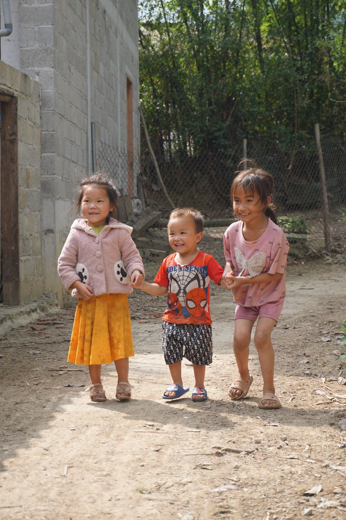 Three children walking hand in hand, laughing